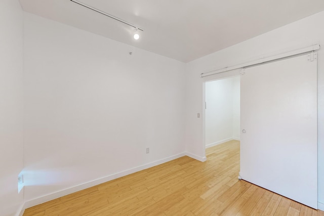 unfurnished bedroom with track lighting, a closet, and light hardwood / wood-style floors