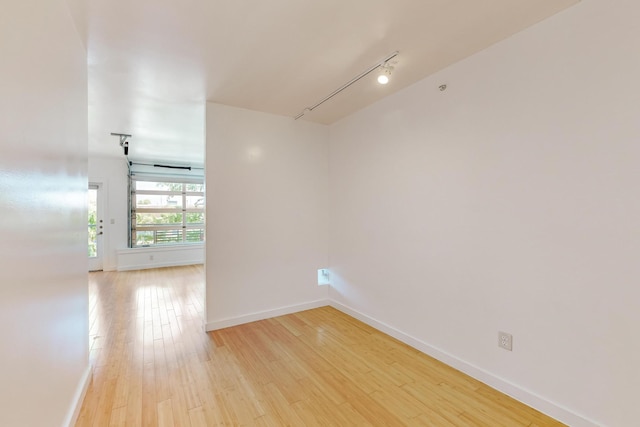 empty room with track lighting and light hardwood / wood-style floors