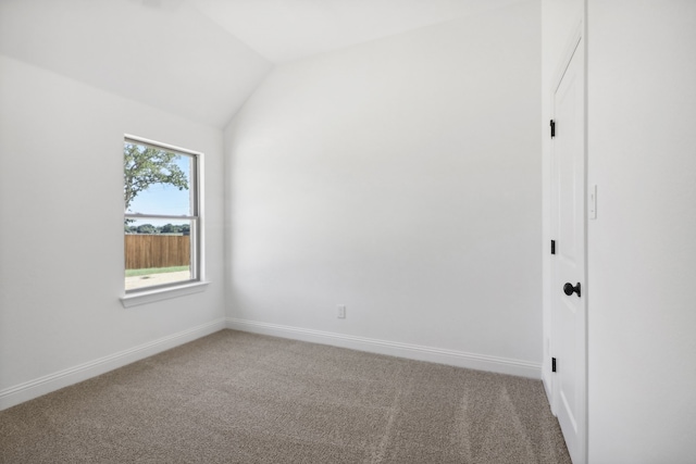 carpeted spare room with vaulted ceiling