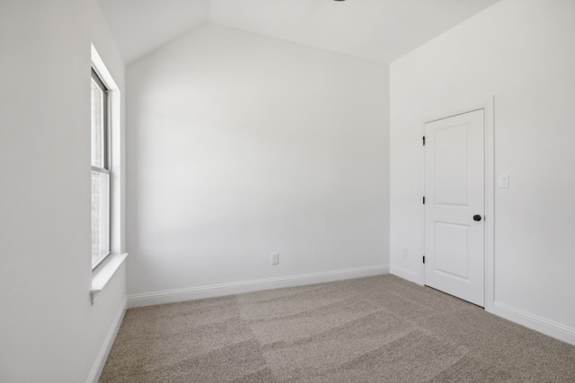 unfurnished room featuring lofted ceiling and light colored carpet