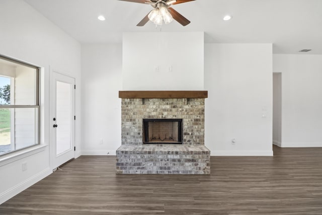 unfurnished living room with a brick fireplace, ceiling fan, and dark hardwood / wood-style floors