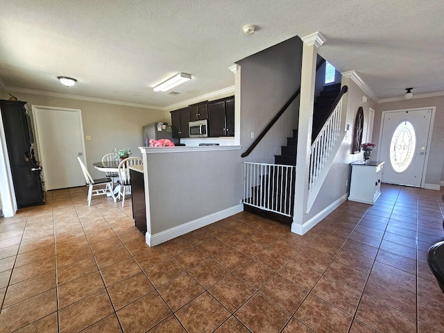 kitchen with appliances with stainless steel finishes, dark tile patterned flooring, and crown molding