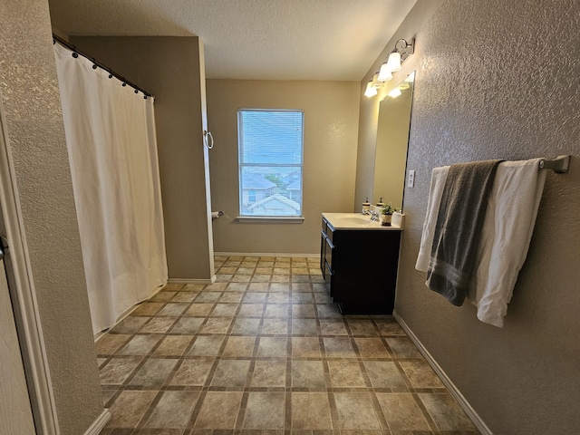 full bathroom featuring baseboards, a textured wall, curtained shower, a textured ceiling, and vanity