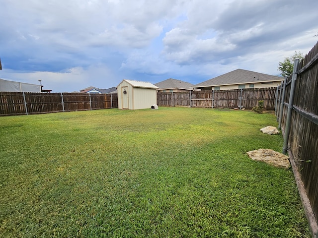 view of yard featuring an outbuilding, a fenced backyard, and a shed