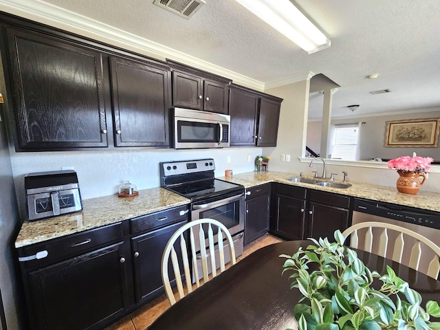 kitchen featuring visible vents, appliances with stainless steel finishes, ornamental molding, a sink, and a textured ceiling