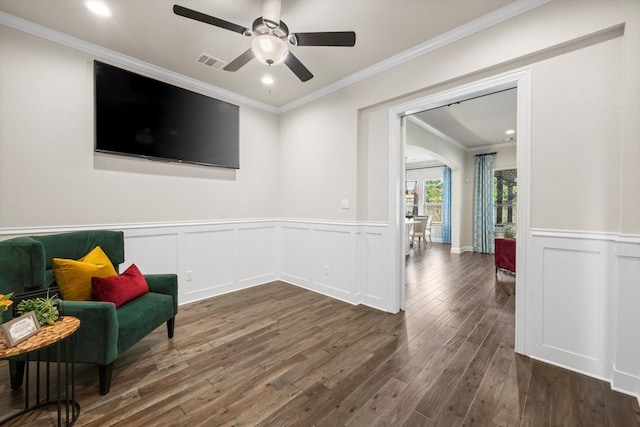 living area with ceiling fan, dark hardwood / wood-style flooring, and ornamental molding