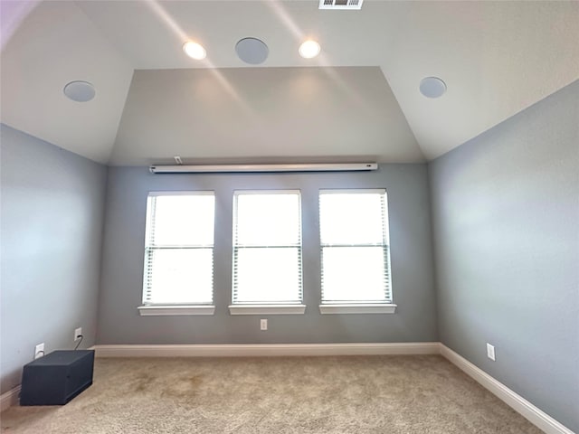 carpeted empty room with plenty of natural light and lofted ceiling