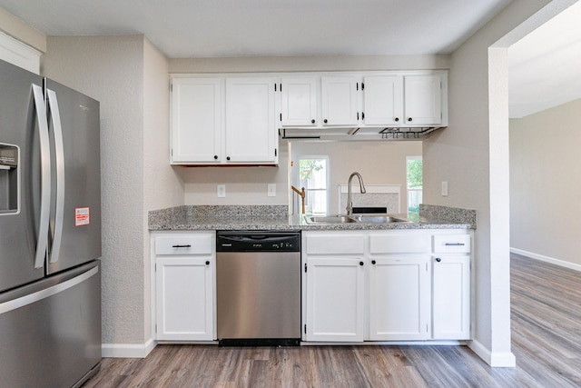 kitchen featuring sink, white cabinets, light stone countertops, light hardwood / wood-style floors, and stainless steel appliances