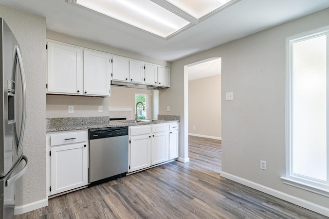 kitchen with white cabinetry, stainless steel appliances, sink, light wood-type flooring, and light stone counters