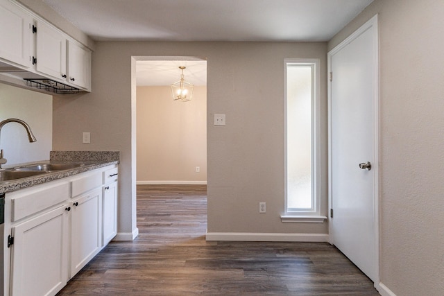 kitchen with white cabinetry, sink, hanging light fixtures, dark hardwood / wood-style floors, and a notable chandelier