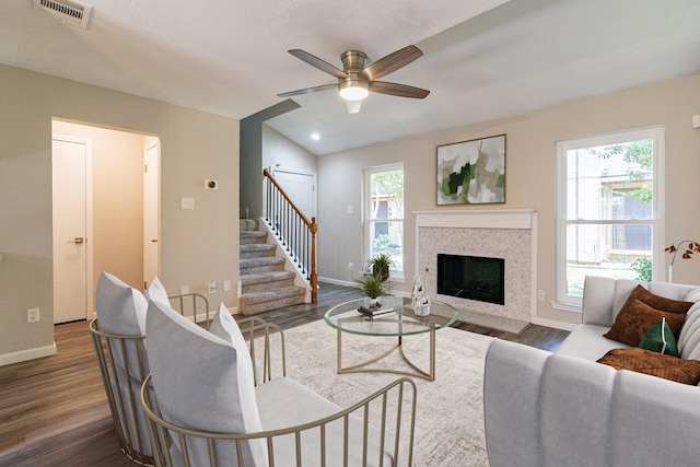 living room featuring dark wood-type flooring, vaulted ceiling, ceiling fan, and a premium fireplace