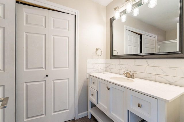 bathroom with a shower with shower door, vanity, and tasteful backsplash