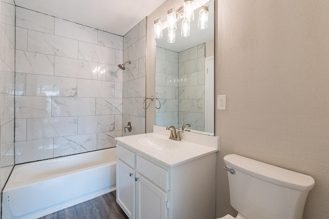 full bathroom with vanity, toilet, hardwood / wood-style floors, and tiled shower / bath combo