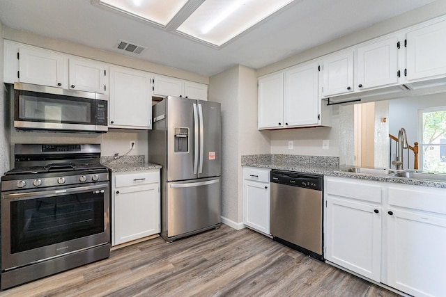 kitchen featuring sink, white cabinets, light wood-type flooring, and appliances with stainless steel finishes