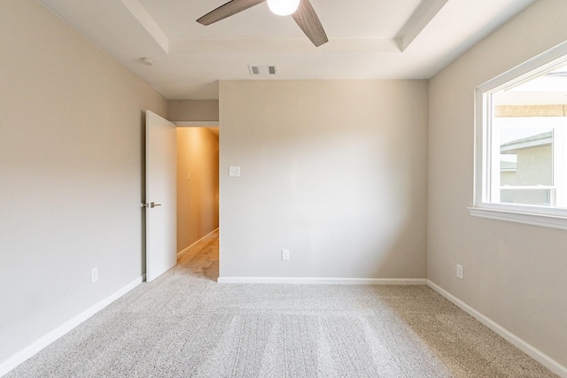 carpeted empty room featuring ceiling fan and a raised ceiling