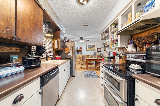 kitchen featuring a textured ceiling, white cabinets, stainless steel appliances, sink, and ceiling fan