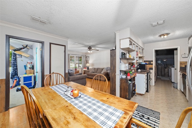 dining area featuring ceiling fan, washing machine and dryer, a textured ceiling, and ornamental molding