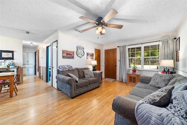 living room with a textured ceiling, ornamental molding, and light wood-type flooring