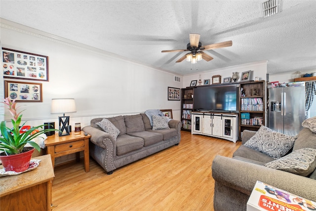 living room featuring hardwood / wood-style flooring, a textured ceiling, and ornamental molding