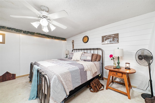 bedroom featuring ceiling fan, a textured ceiling, wood walls, and light carpet