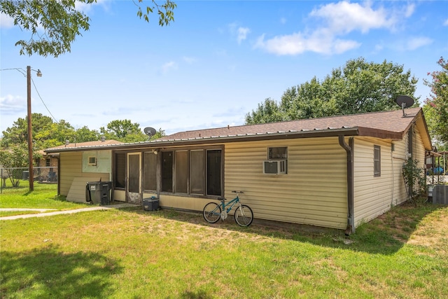 back of house with cooling unit, a lawn, and central air condition unit