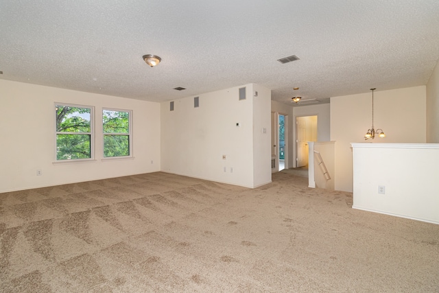 carpeted spare room with a textured ceiling and a chandelier