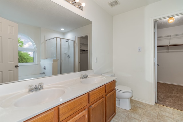 bathroom featuring tile patterned floors, toilet, a shower with shower door, vanity, and a textured ceiling