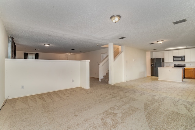 unfurnished living room featuring a textured ceiling and light colored carpet