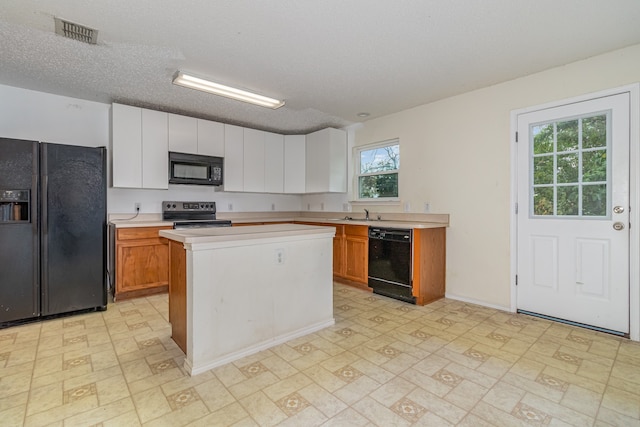 kitchen with white cabinetry, a textured ceiling, black appliances, and a center island