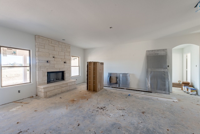 unfurnished living room featuring a stone fireplace and a wealth of natural light