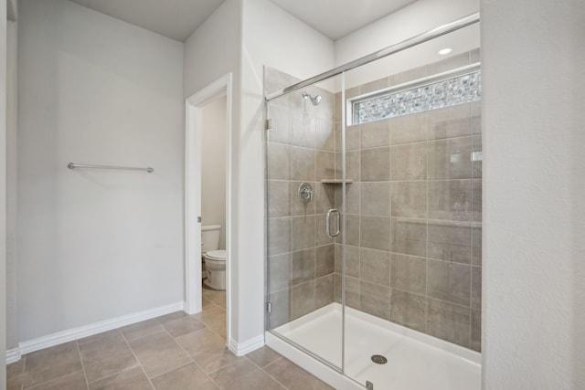 bathroom featuring tile patterned flooring, walk in shower, and toilet