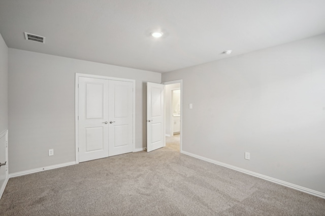 unfurnished bedroom with a closet and light colored carpet