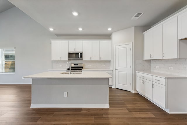 kitchen featuring white cabinets, a center island with sink, appliances with stainless steel finishes, and dark hardwood / wood-style flooring