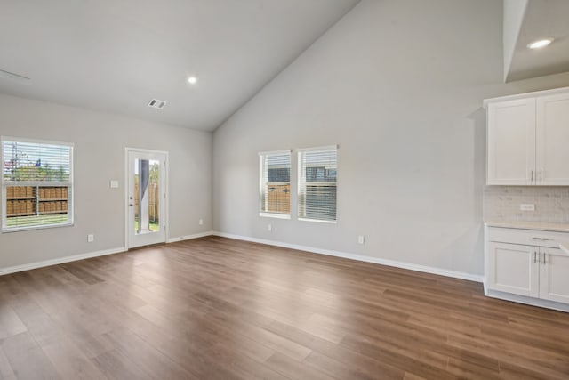 unfurnished living room with high vaulted ceiling and hardwood / wood-style floors