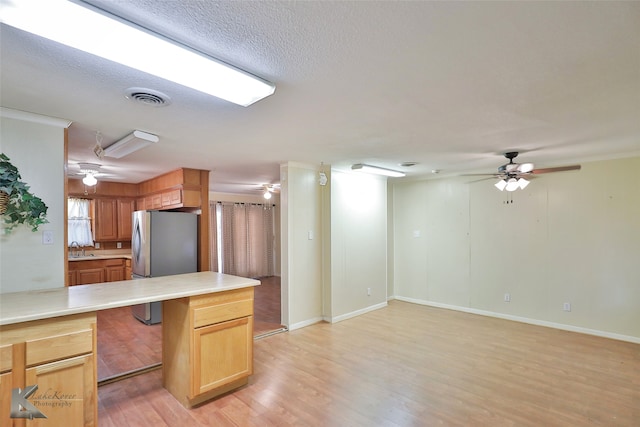 kitchen featuring a kitchen breakfast bar, stainless steel fridge, light hardwood / wood-style floors, kitchen peninsula, and ceiling fan