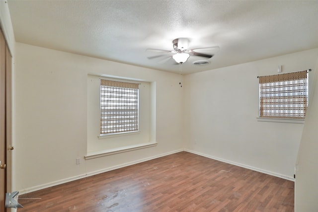 spare room featuring dark hardwood / wood-style flooring, ceiling fan, and a textured ceiling