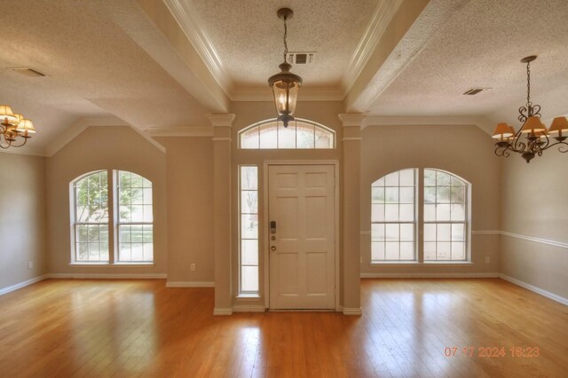 foyer with a chandelier, a textured ceiling, light hardwood / wood-style flooring, and ornamental molding