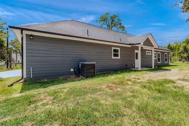 rear view of property with a lawn and cooling unit