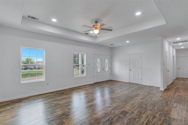 interior space featuring a tray ceiling, ceiling fan, and dark wood-type flooring