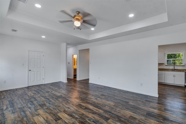 empty room featuring ceiling fan, dark hardwood / wood-style floors, a raised ceiling, and sink