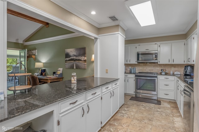 kitchen featuring white cabinets, dark stone countertops, appliances with stainless steel finishes, lofted ceiling, and light tile patterned floors