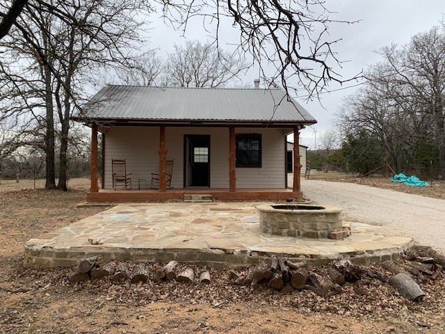 view of outdoor structure featuring a porch and an outdoor fire pit