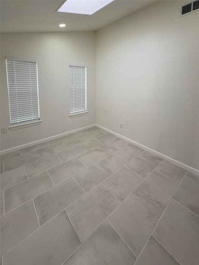 tiled spare room with a skylight