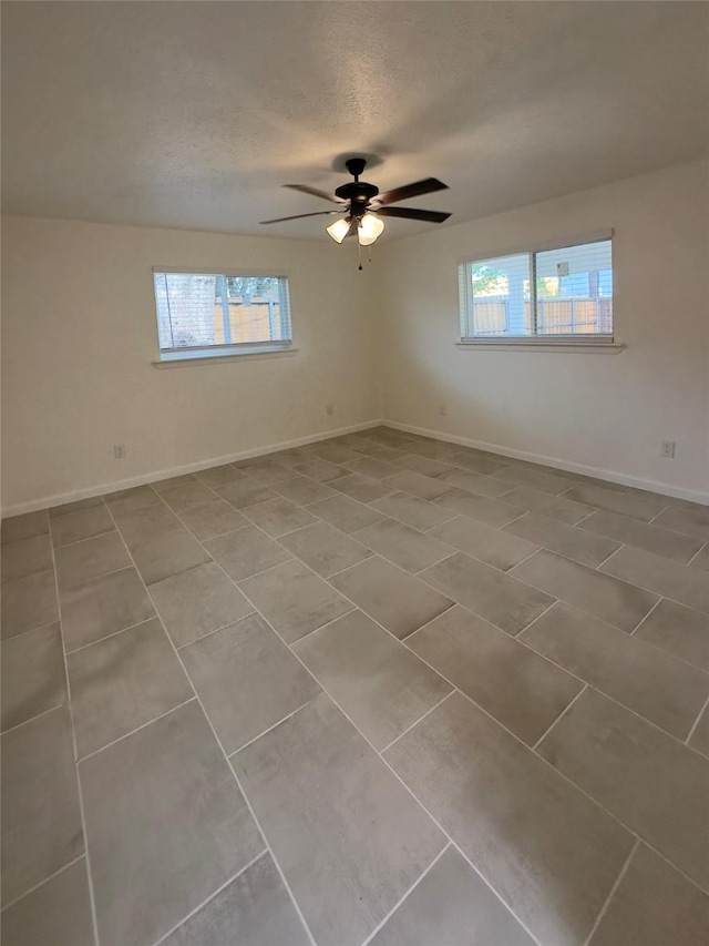 unfurnished room with tile patterned floors, ceiling fan, a healthy amount of sunlight, and a textured ceiling