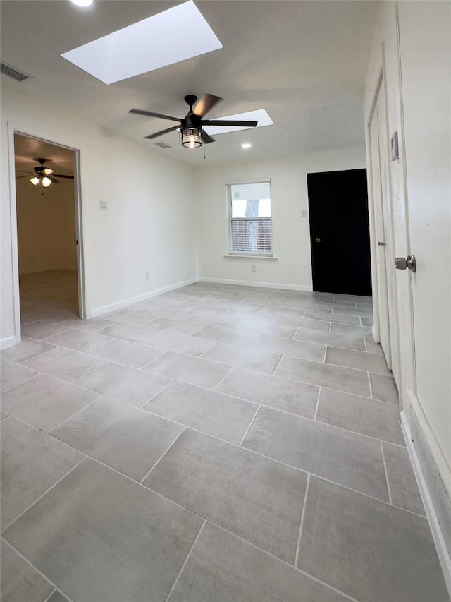 empty room with ceiling fan and a skylight