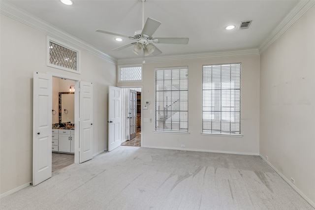 unfurnished bedroom featuring connected bathroom, light colored carpet, multiple windows, crown molding, and ceiling fan