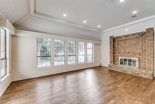 unfurnished living room with brick wall, a brick fireplace, hardwood / wood-style flooring, and vaulted ceiling with beams