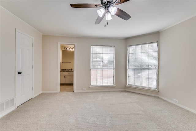 unfurnished bedroom with ornamental molding, ensuite bath, light colored carpet, and ceiling fan