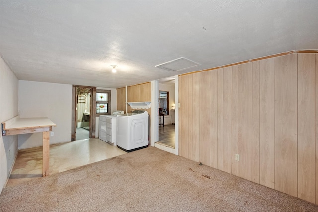 basement featuring light carpet, washer and clothes dryer, and a textured ceiling