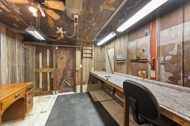 basement with wood walls, a workshop area, and ceiling fan